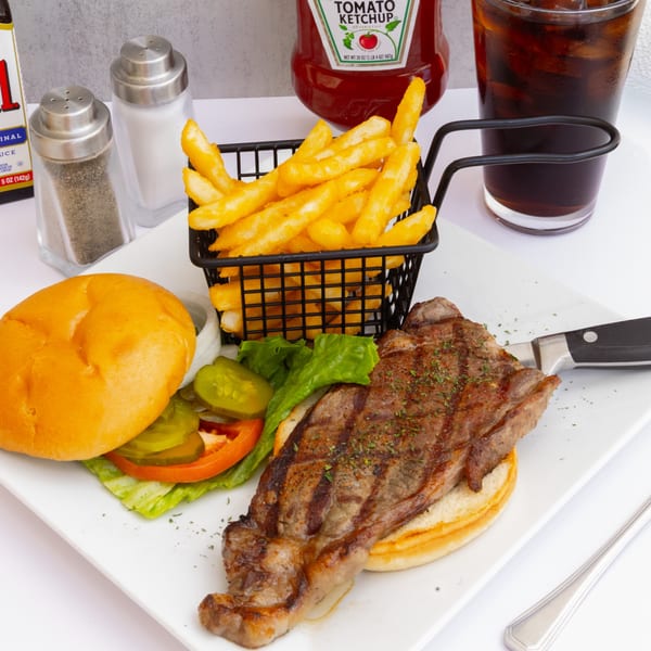 Goldies Restaurant's steak sandwich with fries, ketchup, and a drink on a white plate.