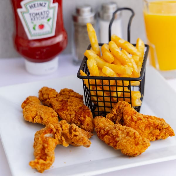 Goldies Restaurant chicken tenders and fries in a basket, with ketchup and orange juice.