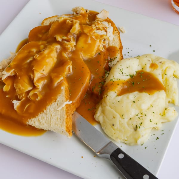 Open-faced turkey sandwich with gravy and mashed potatoes on a white plate at Goldies Restaurant.
