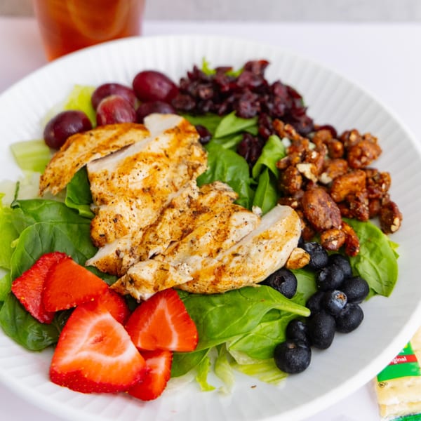 Grilled chicken salad with strawberries, blueberries, grapes, cranberries, and candied nuts.